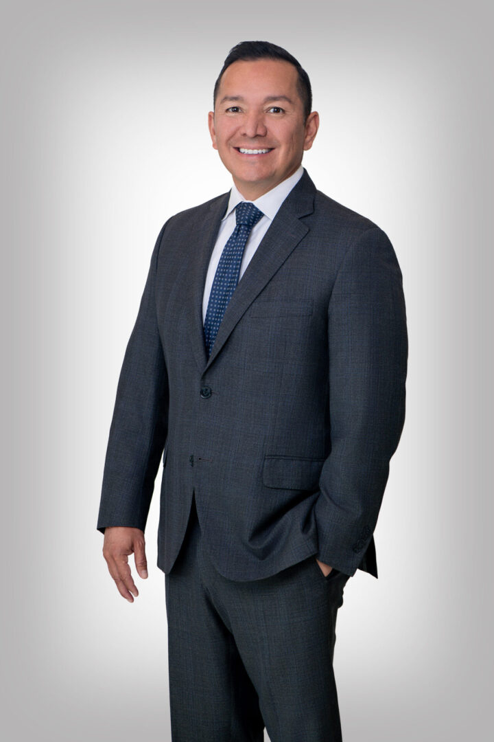 A man in suit and tie standing next to wall.