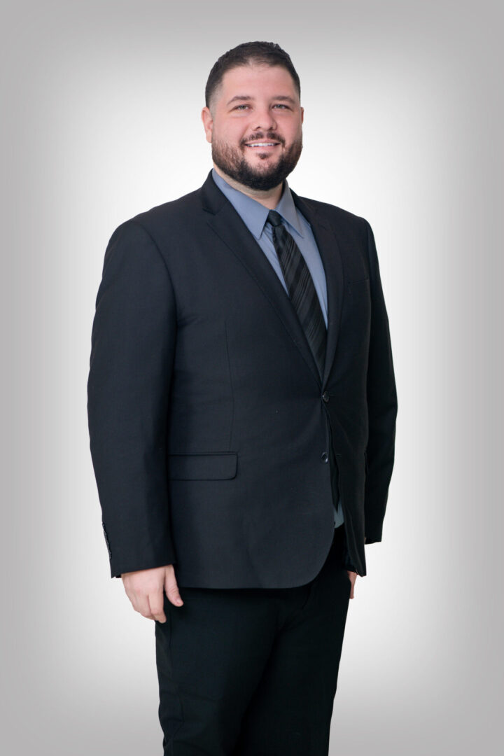 A man in suit and tie standing next to wall.